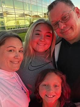Family of four poses at airport.