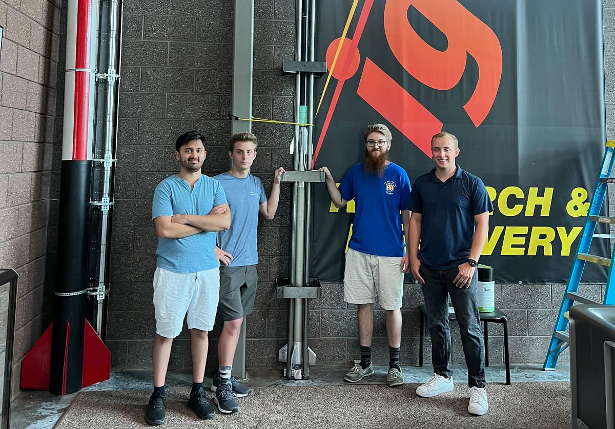 Four students pose in Embry‑Riddle's Aerospace Experimentation and Fabrication Building with their reusable suborbital rocket.