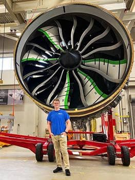 Student stands in front of rocket.