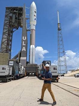Student stands in front of rocket.