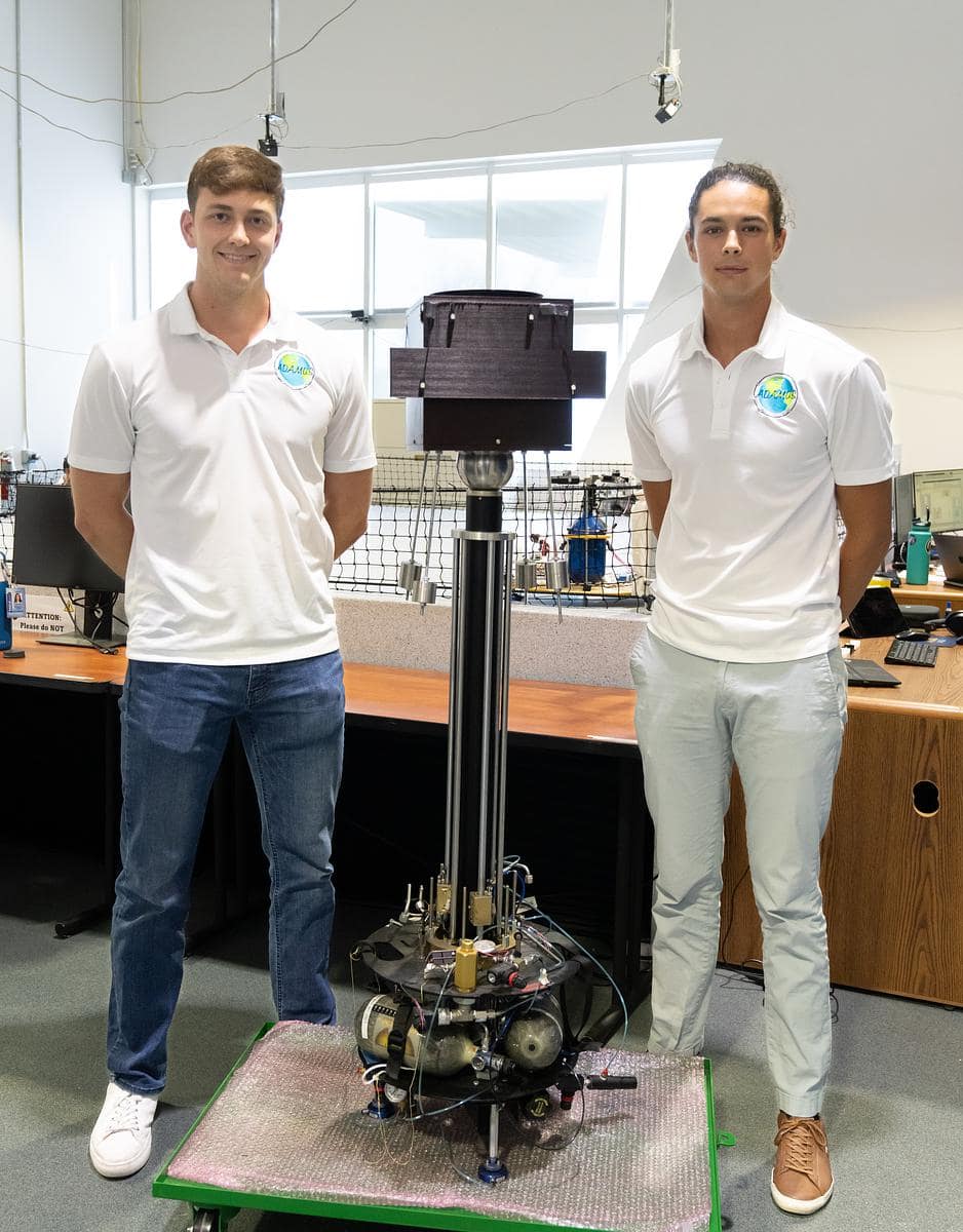 Two students pose next to their model spacecraft.