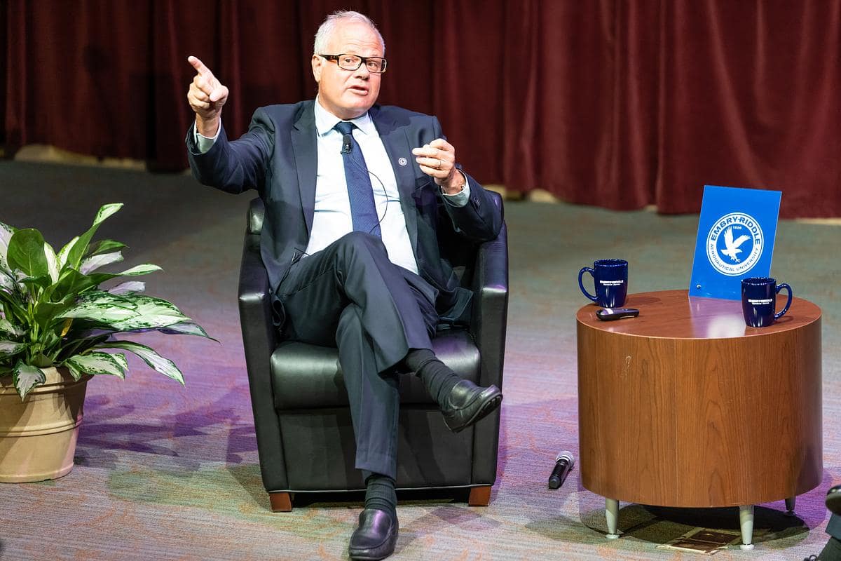 Panda Beting sits in chair on stage pointing to audience.