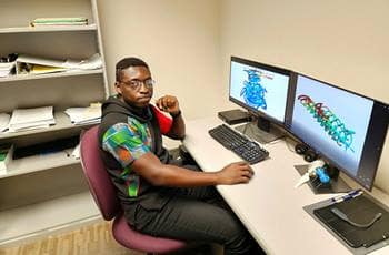 Student sits at desk with two computer monitors.