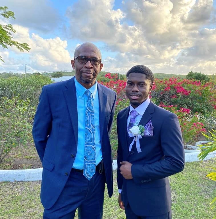 Father and son pose for picture wearing suits.