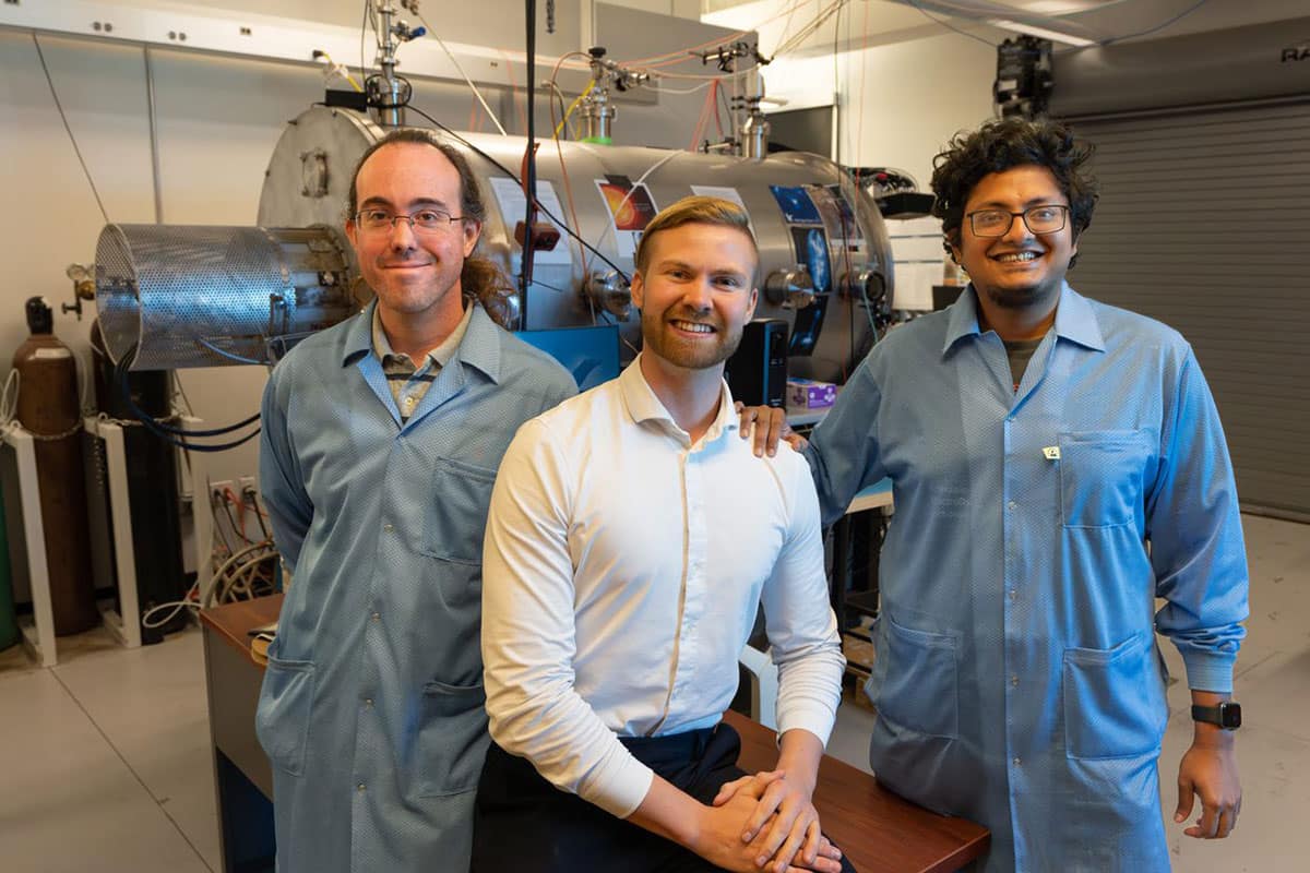 Researchers Robert Clayton, Björn Bergsson and Shantanab Debchoudhury stand in front of the plasma chamber.