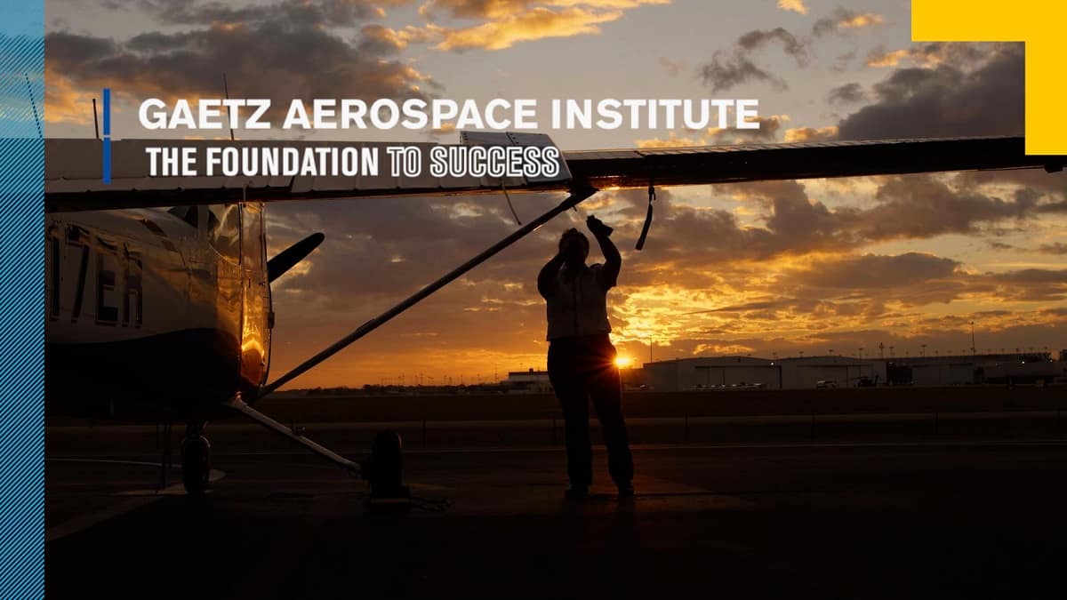 Man works on airplane wing in front of sunset.