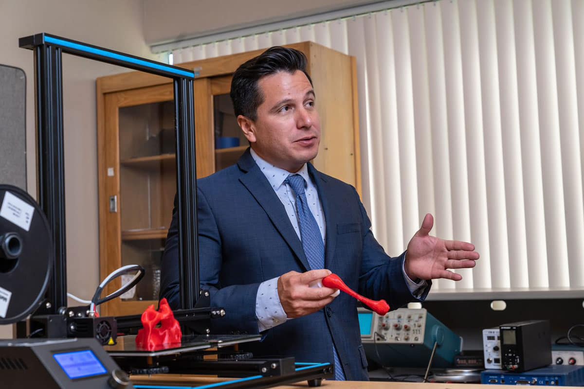 Man in blue suit speaks in lab.