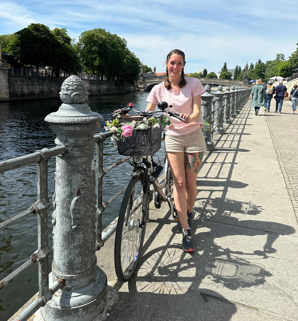 Woman stands next to bicycle on bridge.