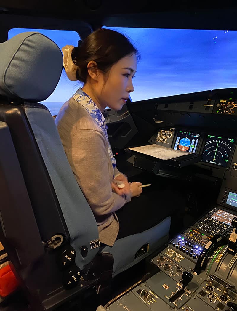 Woman sits in flight simulator.
