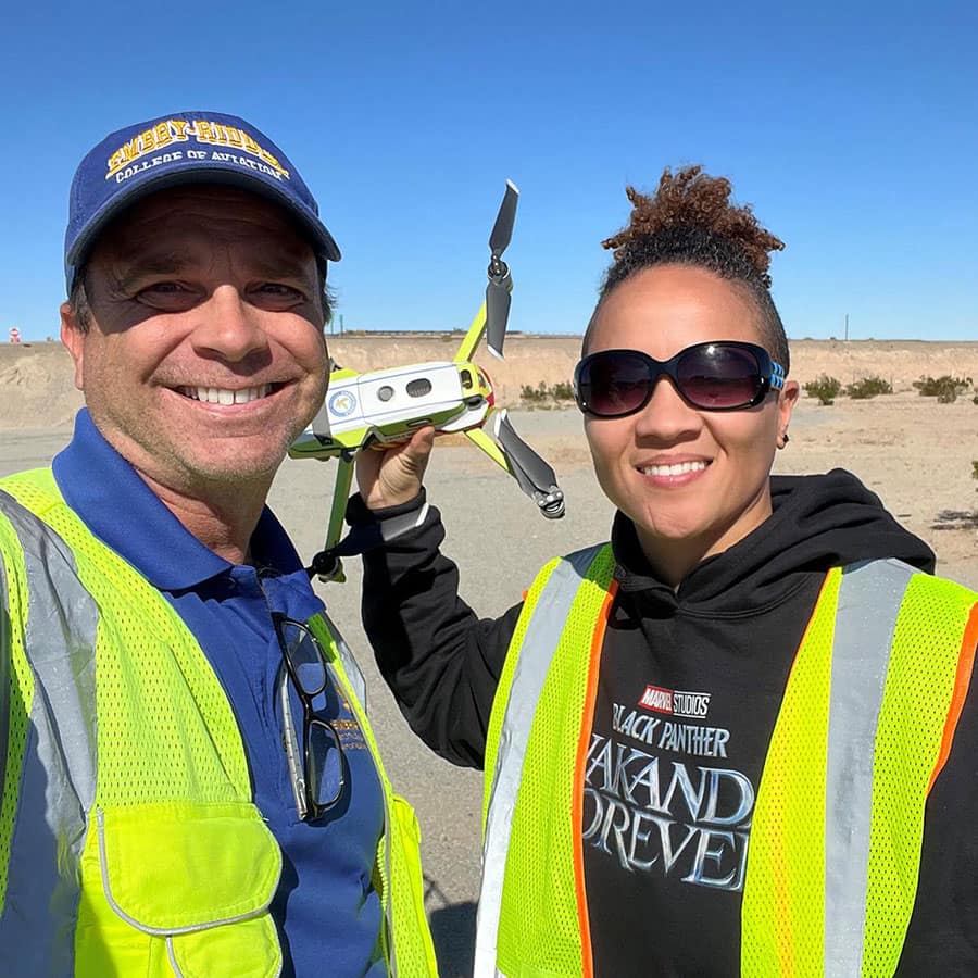 Man and woman pose together holding drone.