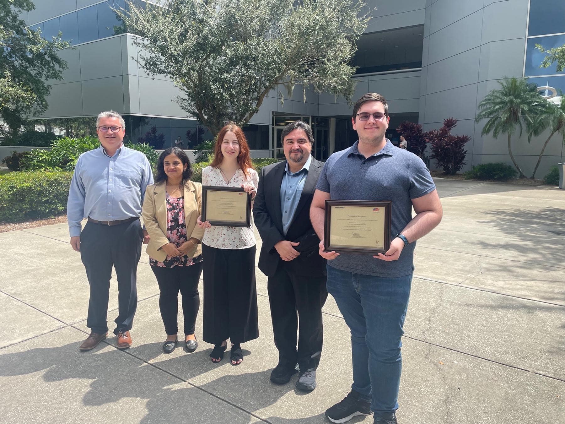 People outside a building holding plaques.