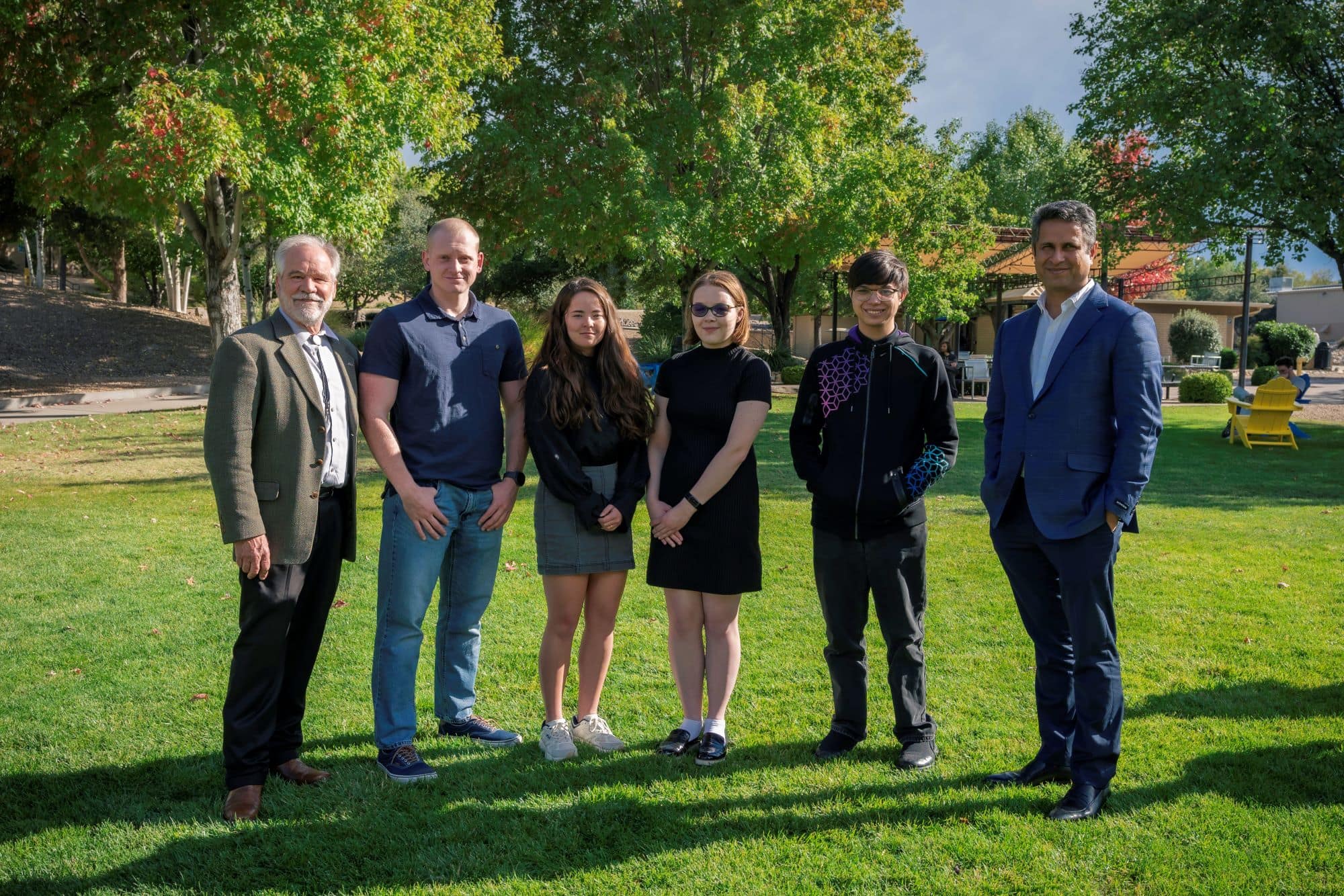 Students and teachers stand in a green field.