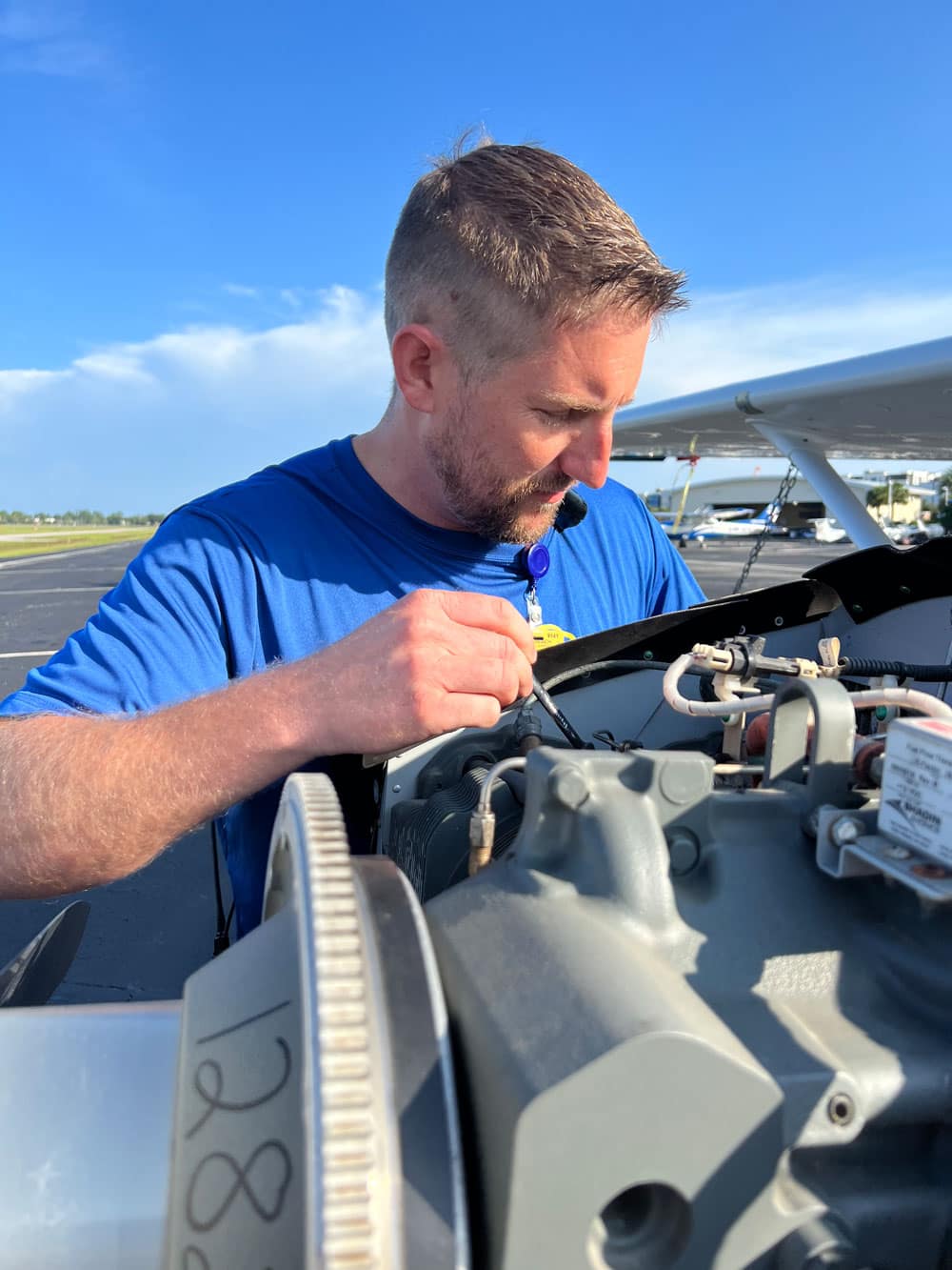 Man works on airplane mechanics outdoors.