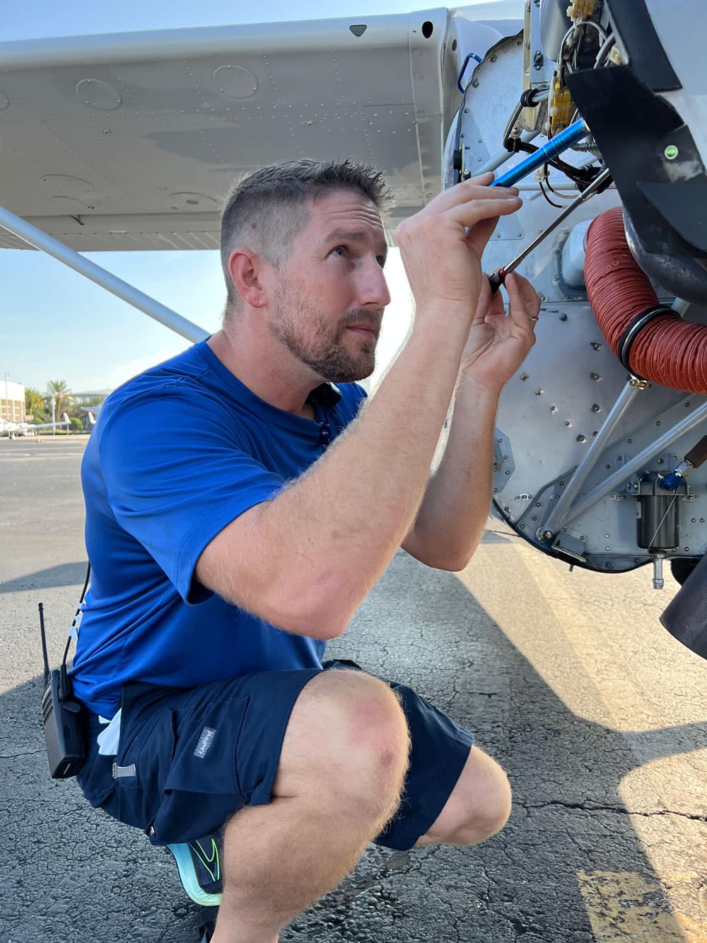 Man works on airplane mechanics outdoors.