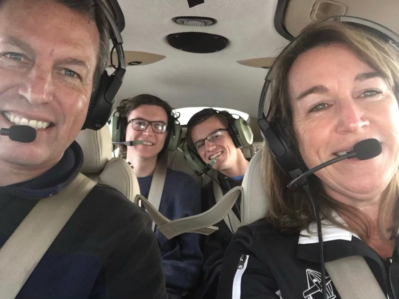 Family of four sits in airplane.