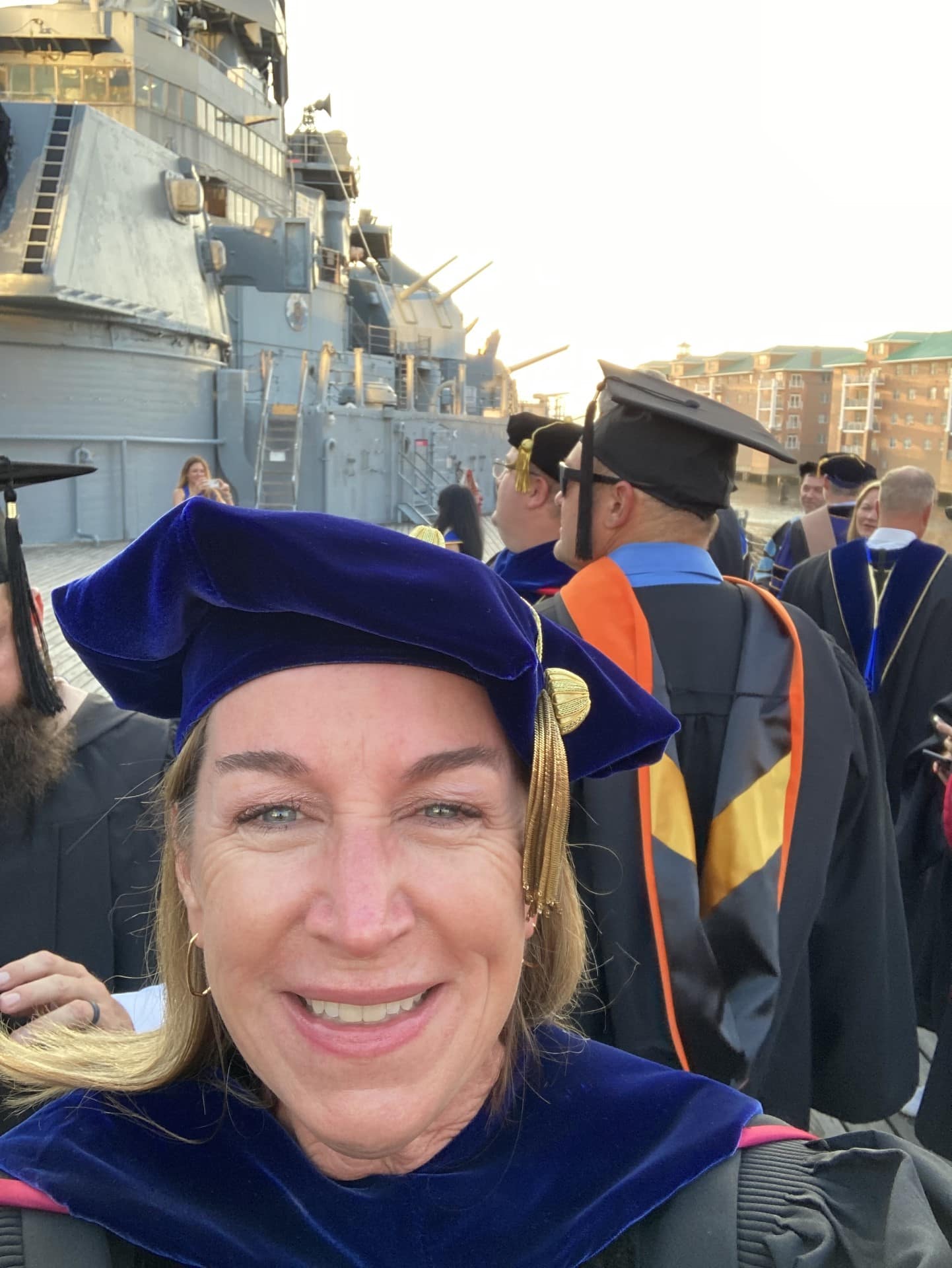 Woman poses in cap and gown at a graduation ceremony.