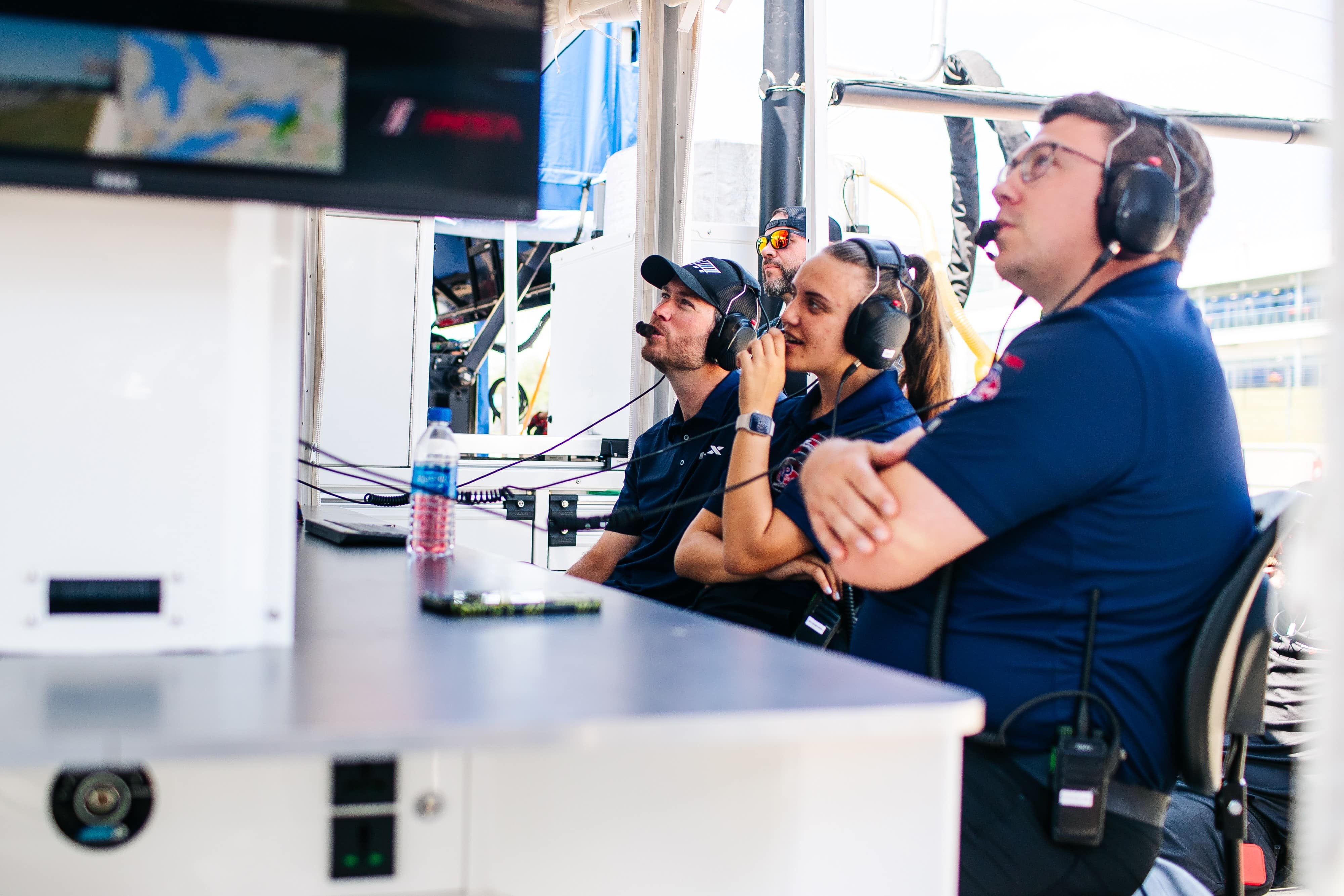 People with headsets monitor a race.