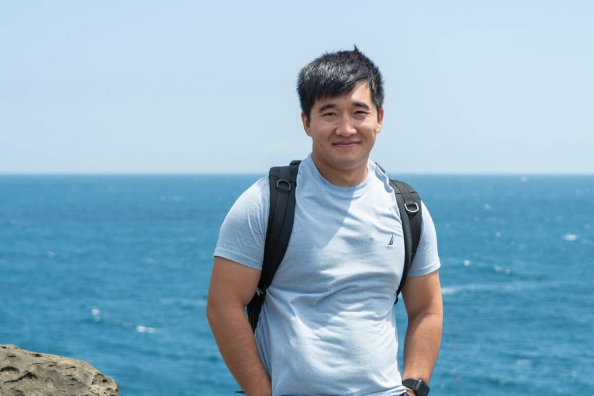 A man stands in front of an ocean vista