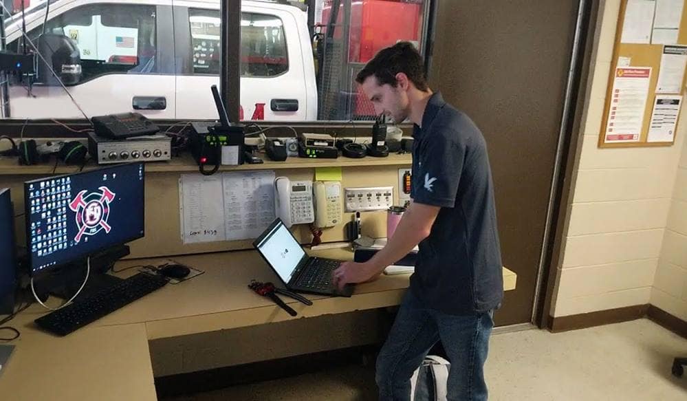 A man works at a desk on a computer in a small industrial office.