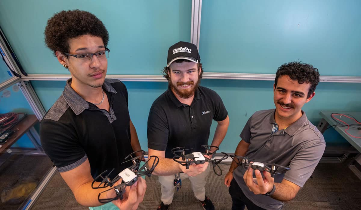 Three students hold drones.