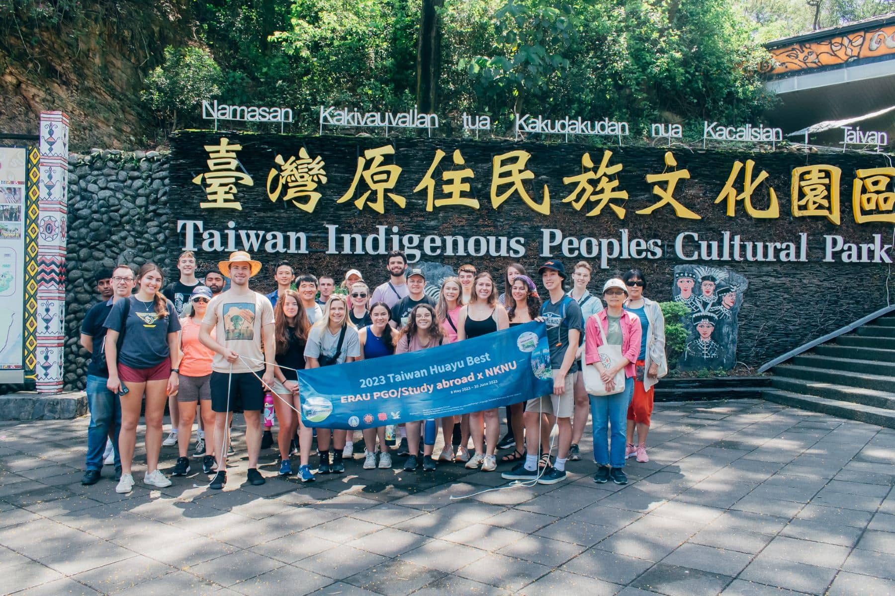 Students pose with a sign in front of Taiwan Indigenous Peoples Cultural Park.