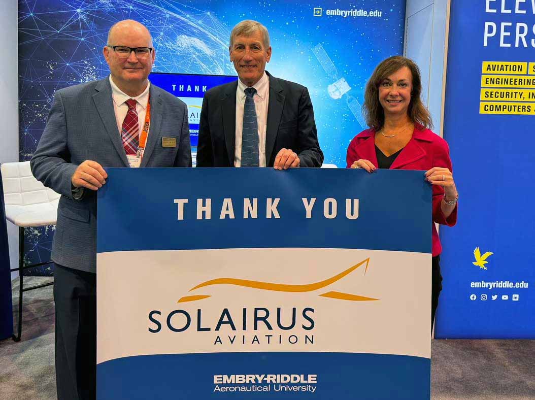 Three people hold up a "Thank You Solairus Aviation" sign.
