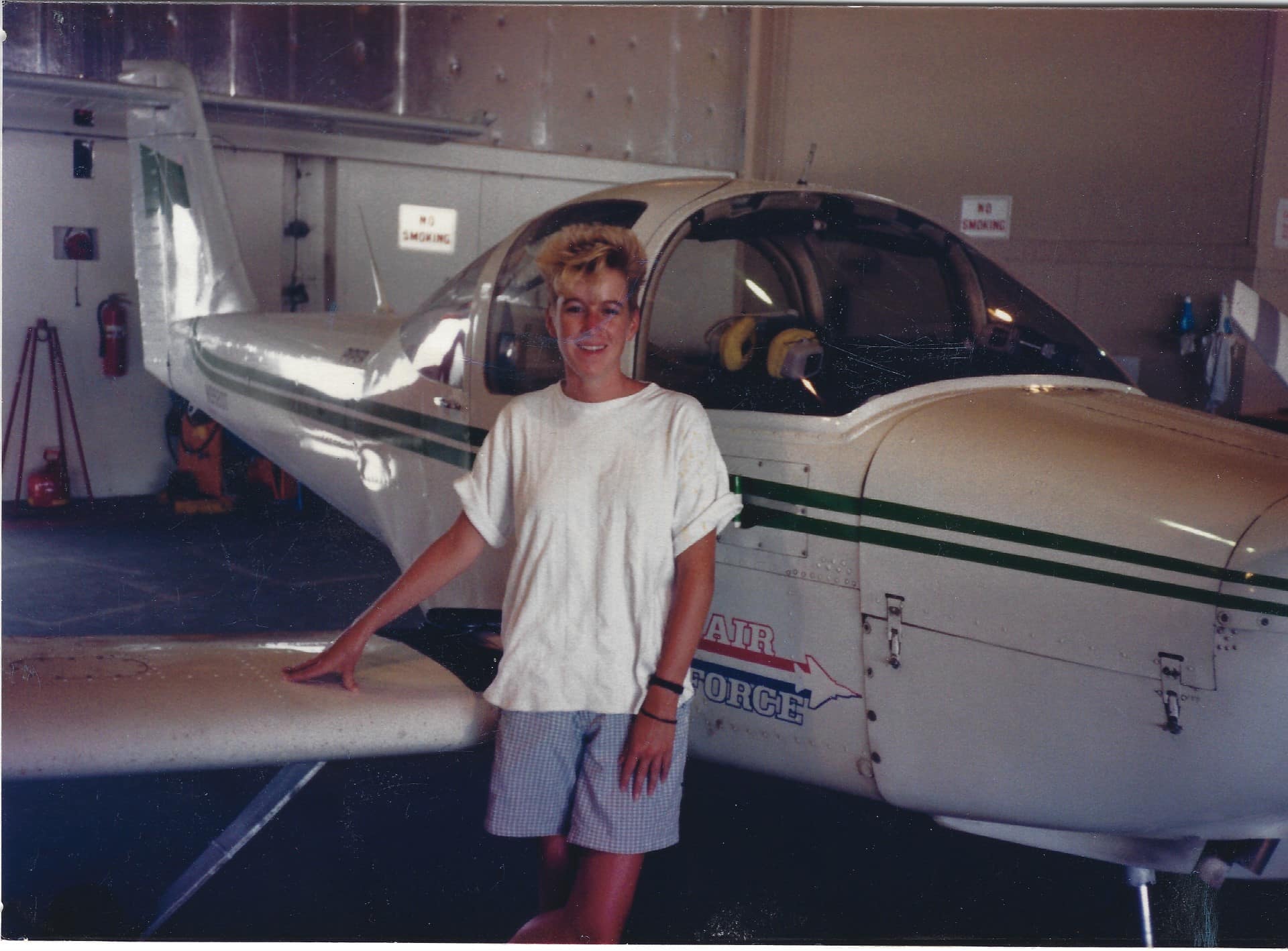 Woman stands in front of airplane.