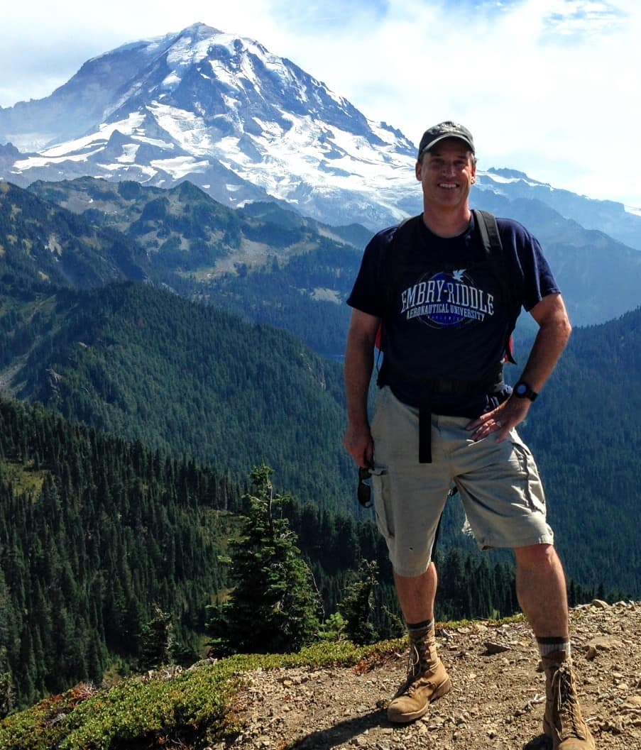 Man stands in front of mountain.