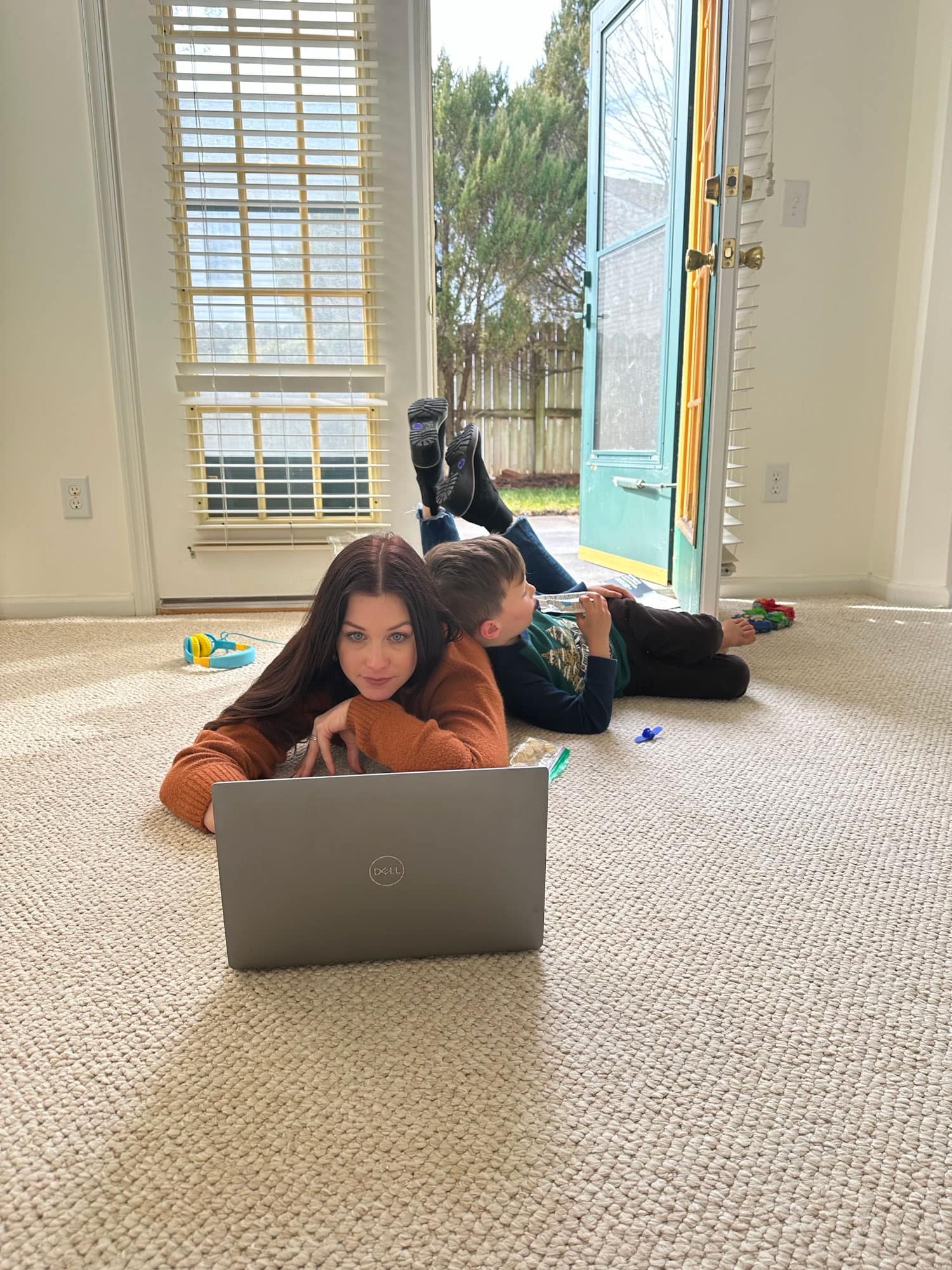 Woman and child lay on floor looking at laptop