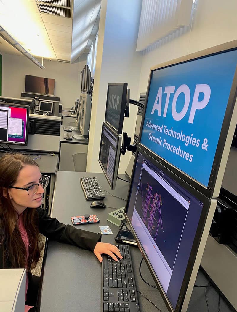 A woman at a desk on a computer in a lab classroom.