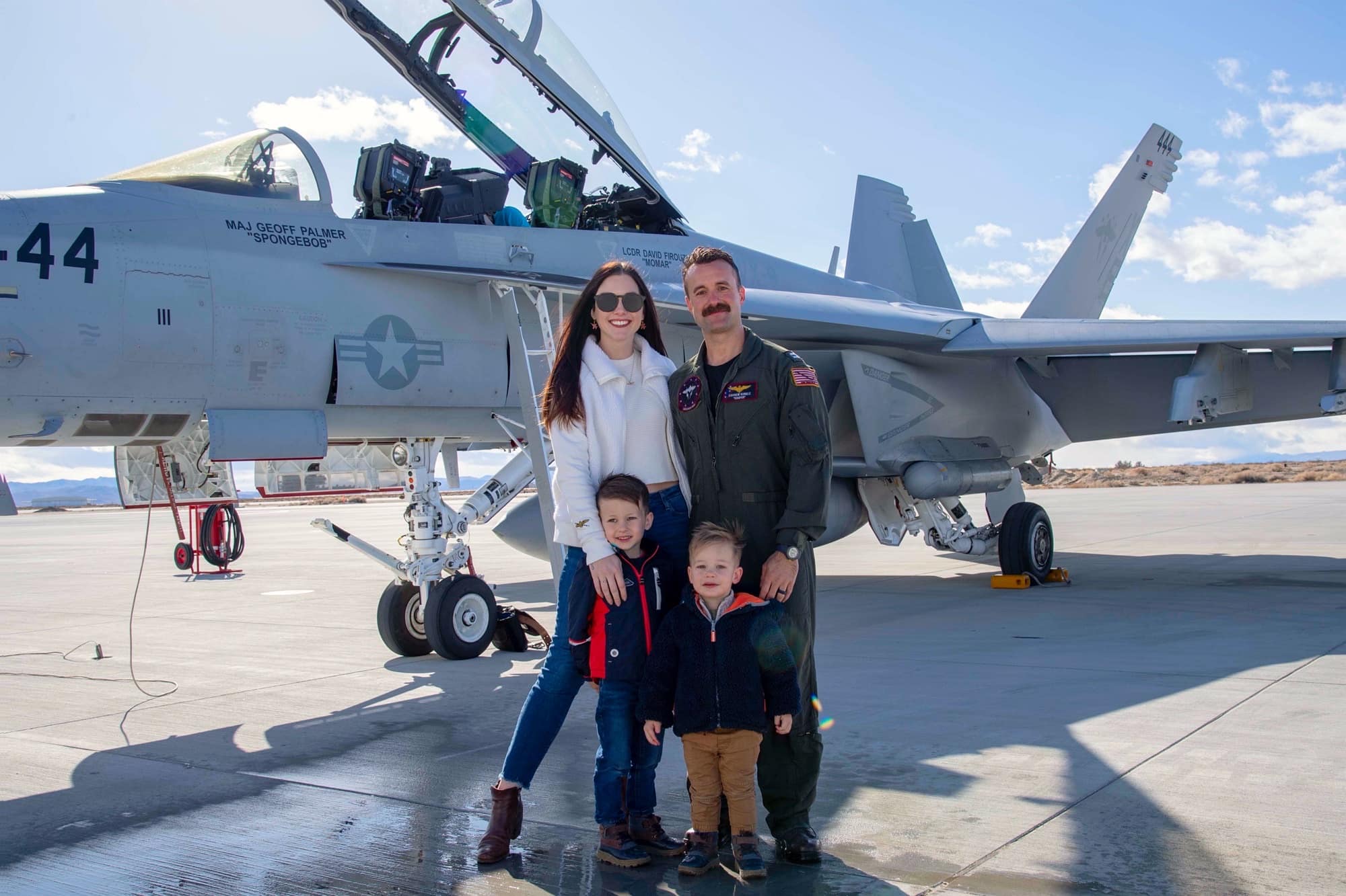 Family poses in front of fighter jet.