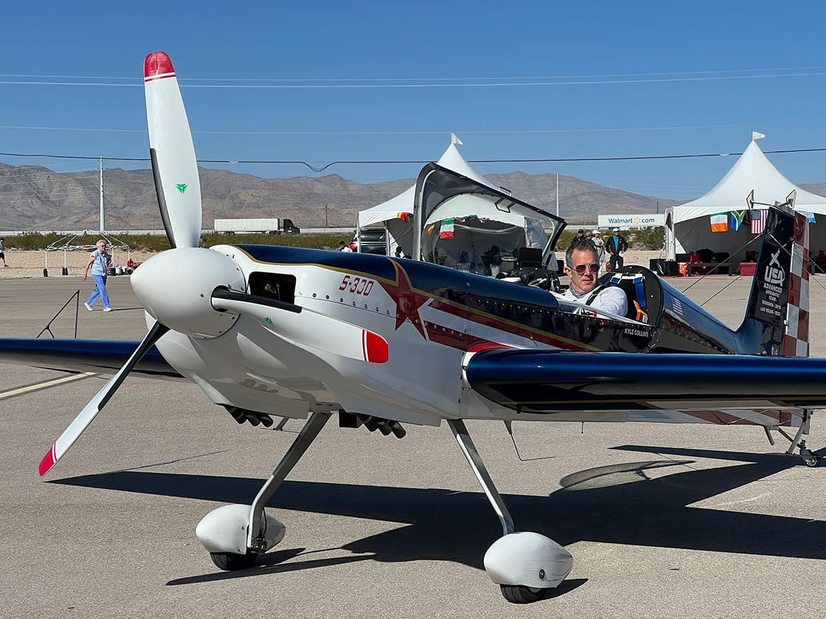 Man sits in small airplane on runway.