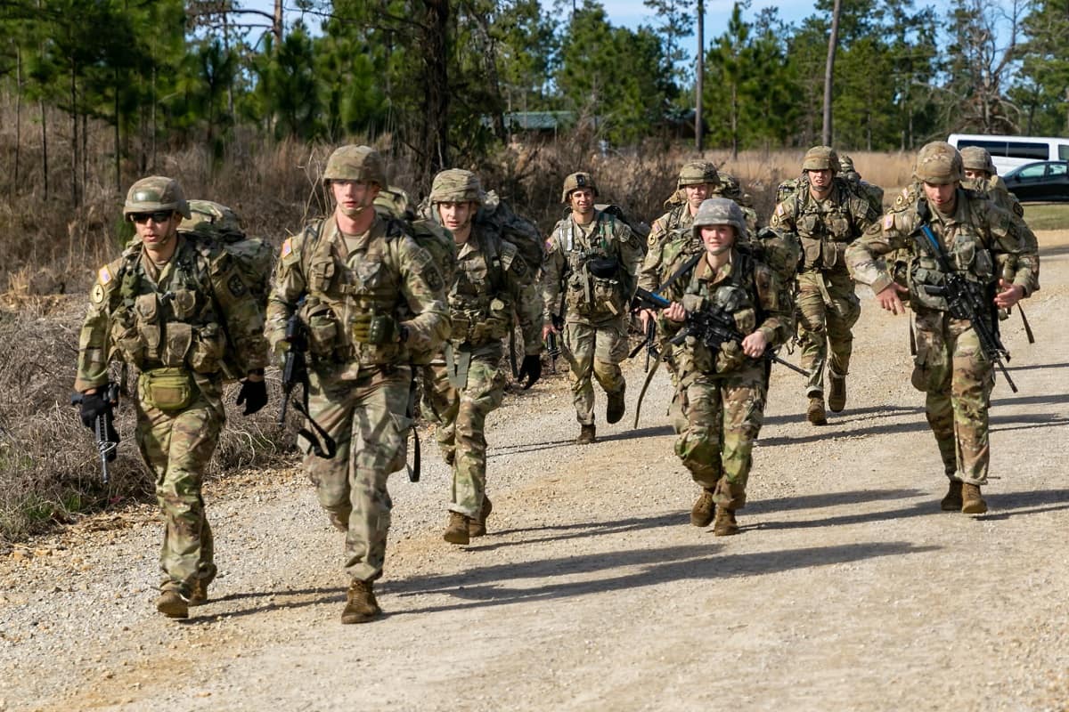 Group of Army Rangers march on gravel road.