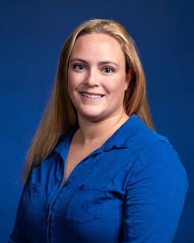 Studio portrait of Sam Bowyer in a bright blue blouse.