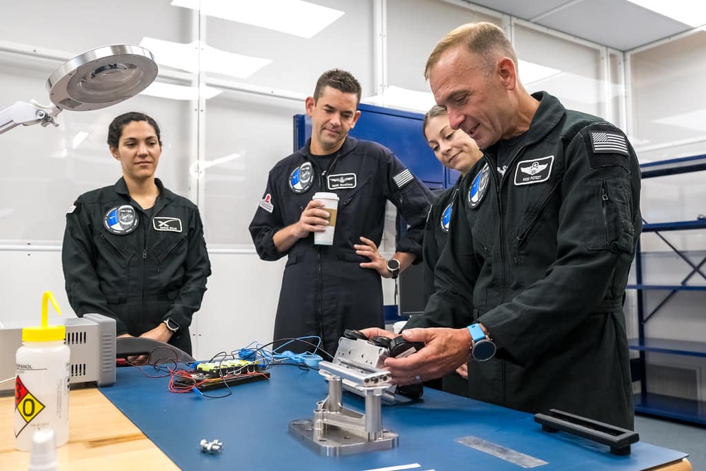 Polaris Dawn Mission Pilot Scott Poteet (right) inspects the LLAMAS camera unit, engineered by Embry‑Riddle students under the direction of Dr. Troy Henderson, associate professor of Aerospace Engineering and director of the Space Technologies Lab. Alongside Poteet are fellow crewmembers Anna Menon, Embry‑Riddle alumnus Jared Isaacman ('11) and Sarah Gillis. (Photo: Polaris Program/John Kraus)