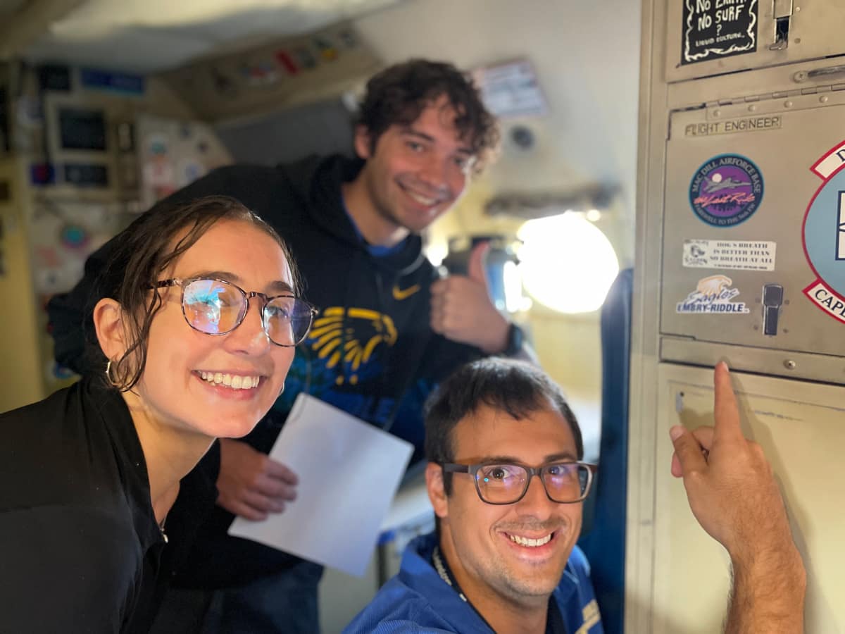  Dr. Josh Wadler (bottom) shows off an Embry‑Riddle decal in the Lockheed WP-3D Orion plane used by NOAA to fly through hurricanes. Next to him (left) is NOAA Flight Director Sofia de Solo, an Embry‑Riddle alumna, and undergraduate Christopher DeLoach (back).