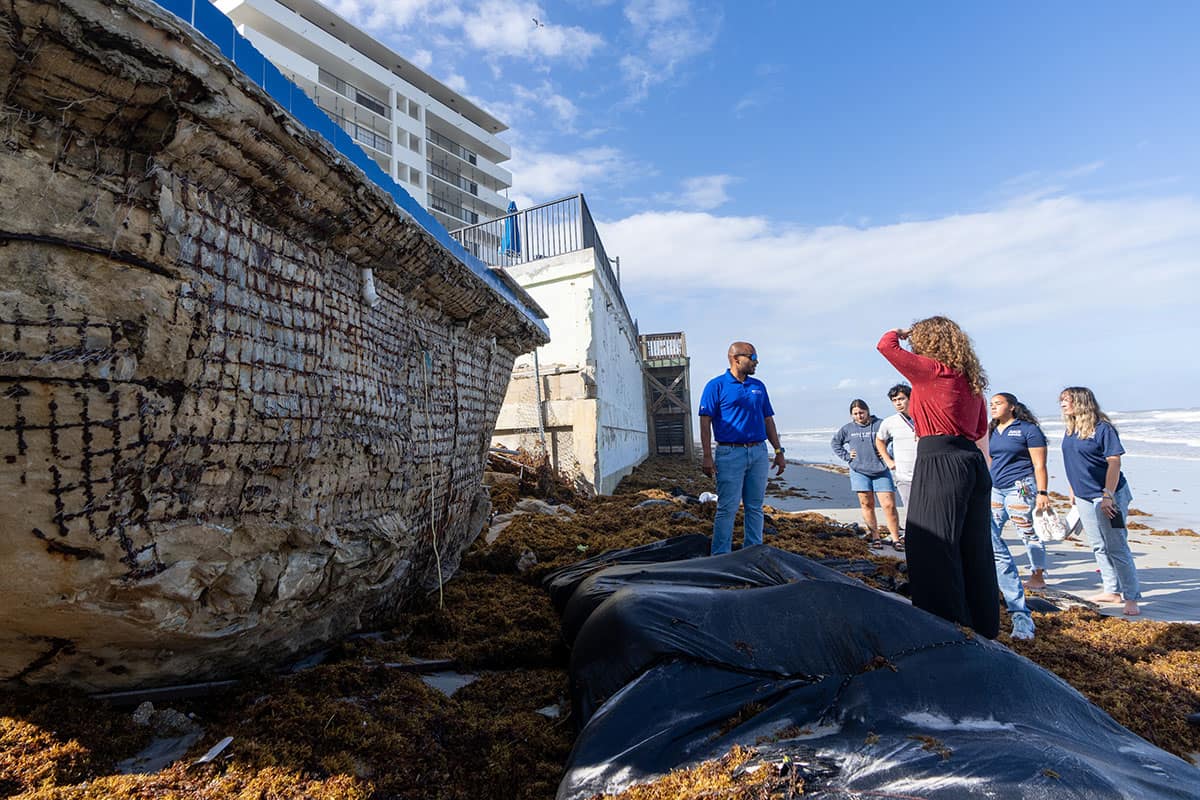 Embry‑Riddle Professor Siddharth Parida and students involved in the Living Seawall project look at a site where storm surge has ripped away the beach-facing side of a swimming pool on Daytona Beach’s shoreline. (Photo: Embry‑Riddle/David Massey)