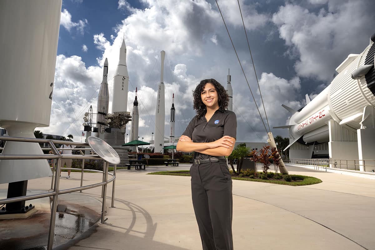 Aviation Week 20 Twenties honoree Liz Bosch stands between a Delta II (left) and a Saturn 1B in the Rocket Garden at Kennedy Space Center. She is one of four Embry‑Riddle students named to the 2025 class. (Photo: Embry‑Riddle/Bill Fredette-Huffman)