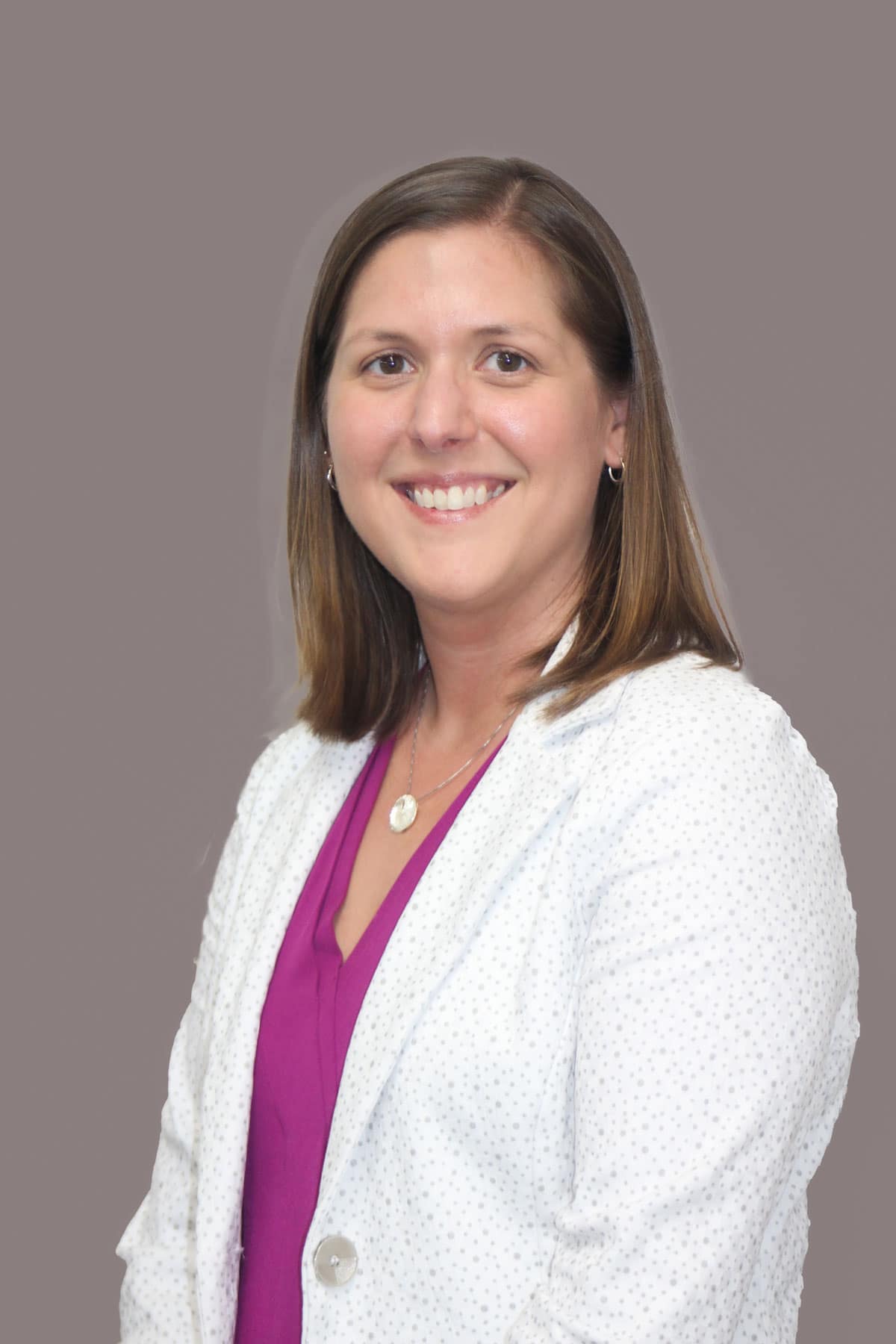 Portrait of Jennifer Schaeffer, wearing a white blazer and pink blouse. 