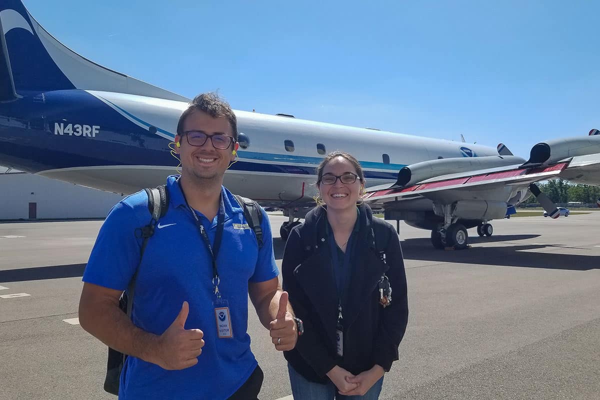 Dr. Josh Wadler and Lauren Villafane, an Embry‑Riddle graduate and National Weather Service forecaster, pose in front of a National Oceanic and Atmospheric Administration (NOAA) Hurricane Hunter WP-3D Orion aircraft. (Photo: Laura Chaibongsai/NOAA)