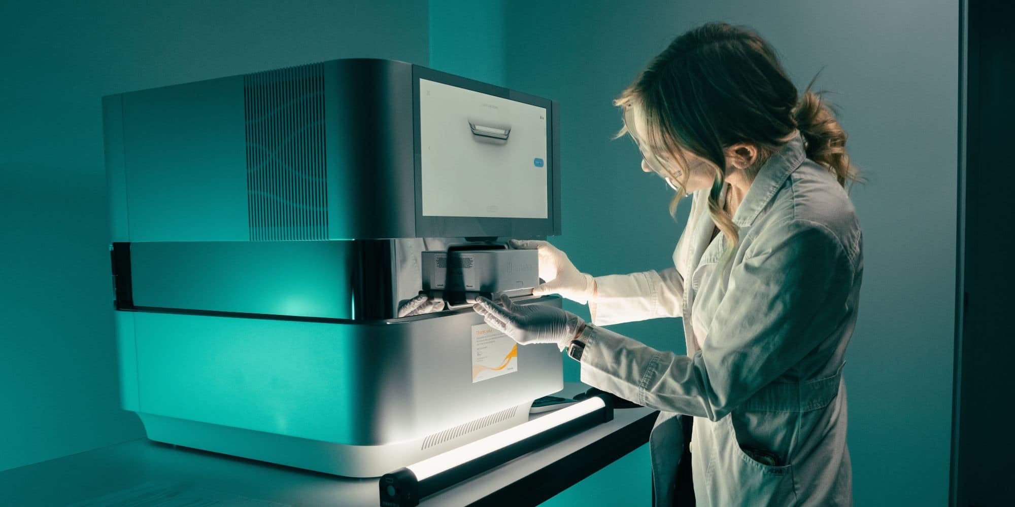 A lab technician inserts a sample into a benchtop analyzer.