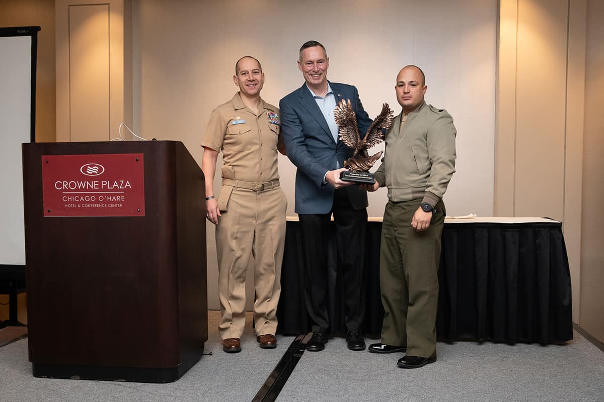 Embry‑Riddle’s senior enlisted Marine staff member, Gunnery Sgt. Felix Arroyo Robles (right), was recently named the 2023 NROTC Assistant Marine Officer Instructor of the Year by USAA. He is pictured here with Embry‑Riddle NROTC Commanding Officer Capt. Carlos Medina (left) and USAA award presenter Michael Magnetta (center). (Photo: Mack Jamieson)