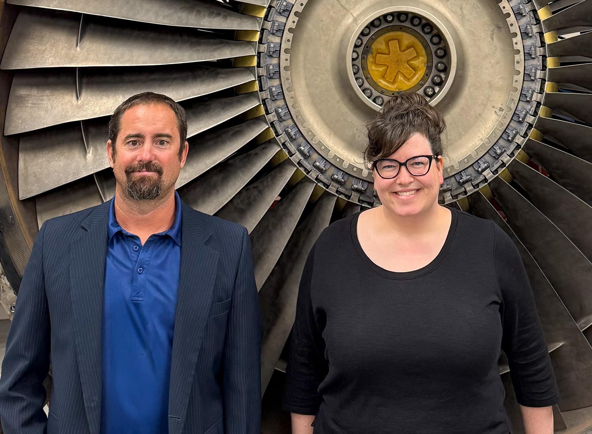 Drs. Sandra Boetcher and Mark Ricklick, standing in front of an aircraft turbine.