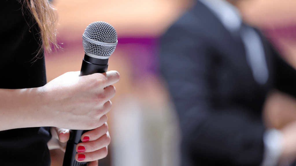 Photo of a person holding a microphone during a presentation.