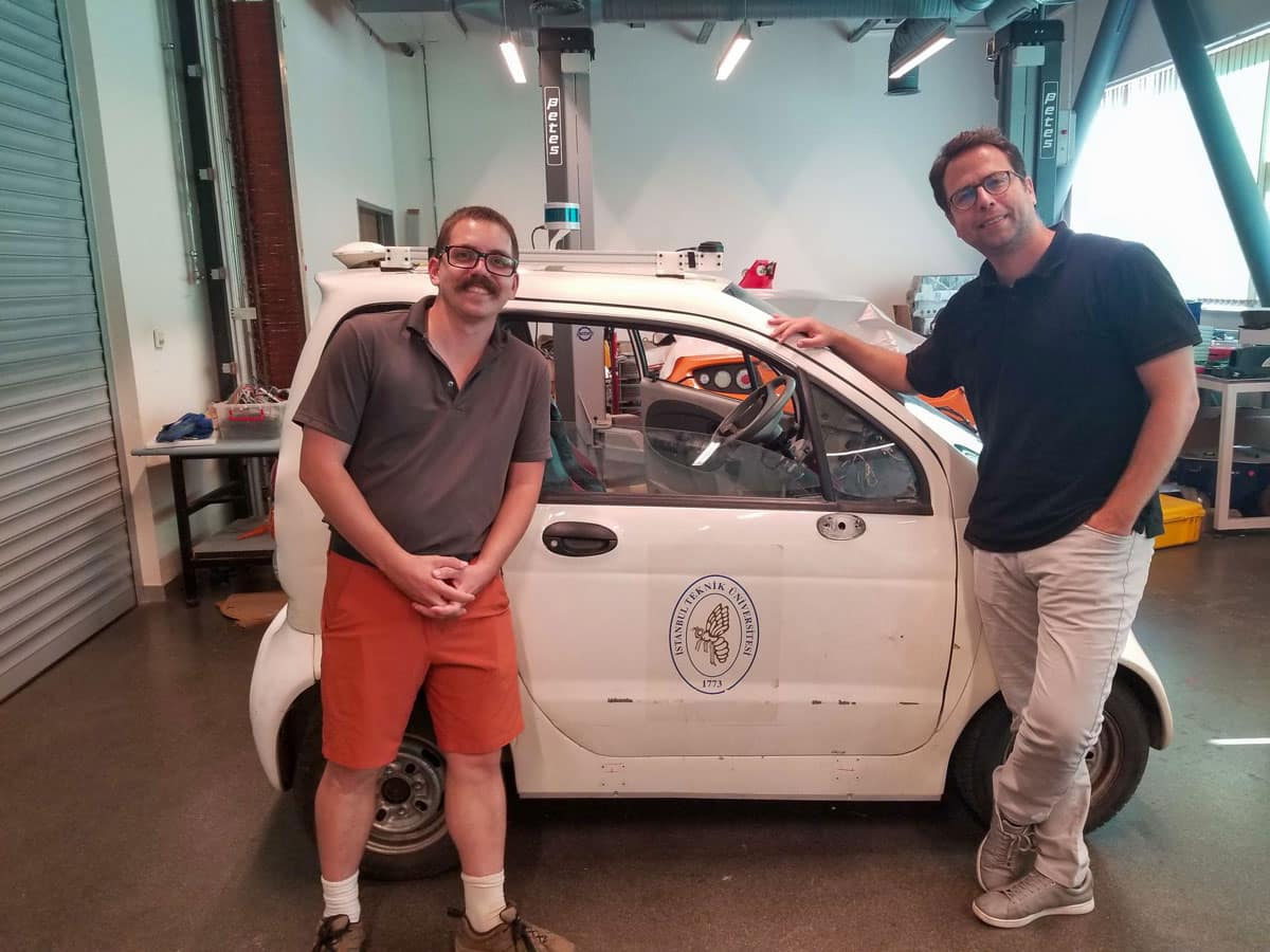 Quentin Goss and Dr. M. Ilhan Akbas stand in front of a car at Istanbul Technical University's E-Mobility lab.