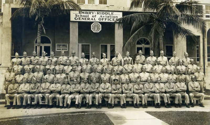 A cadet class poses outside the entrance of Embry‑Riddle School.