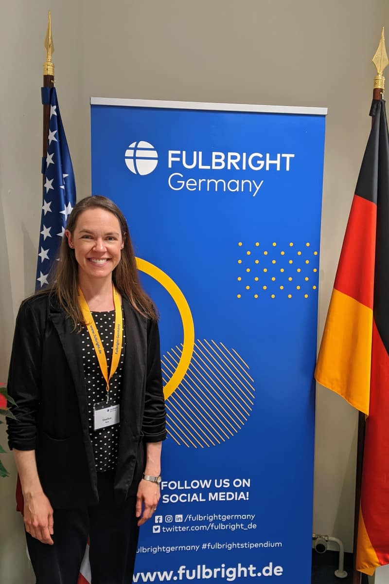 DeeAnn Resk in front of banner at Fulbright Germany Headquarters in Berlin