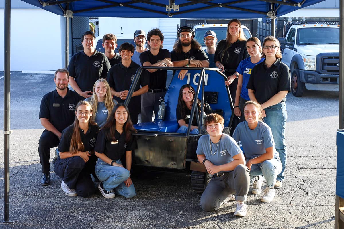 Embry-Riddle's Baja SAE team stands in front of its tracked vehicle.