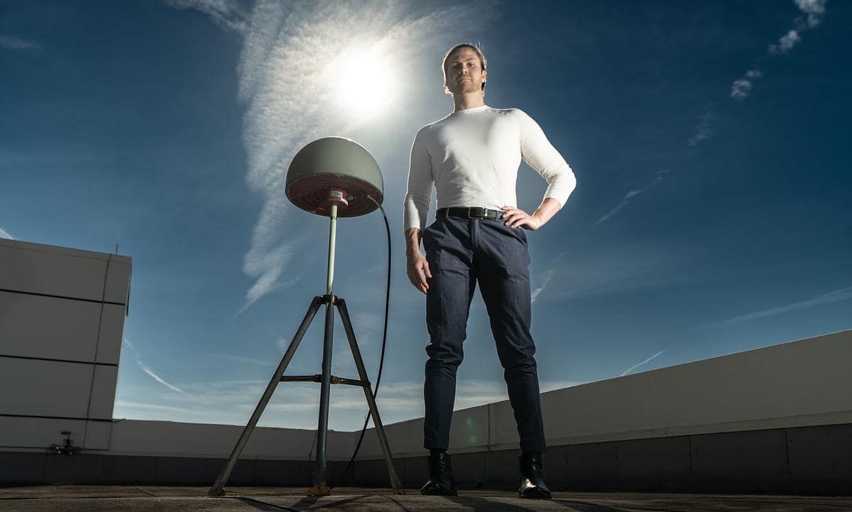 Engineering Physics Ph.D. candidate Björn Bergsson stands next to one of several high-precision Global Navigation Satellite System antennas on roof.