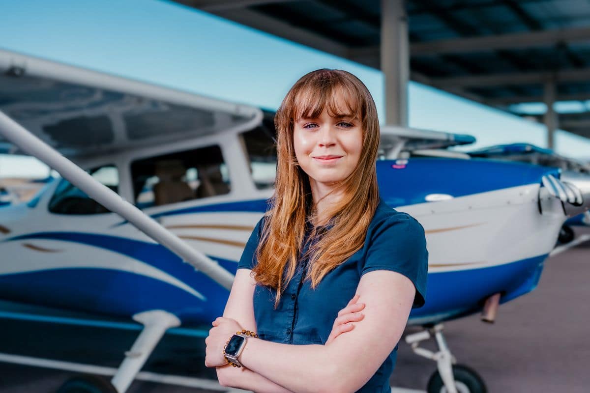 Cassidy Blackwood stands in front of airplane.